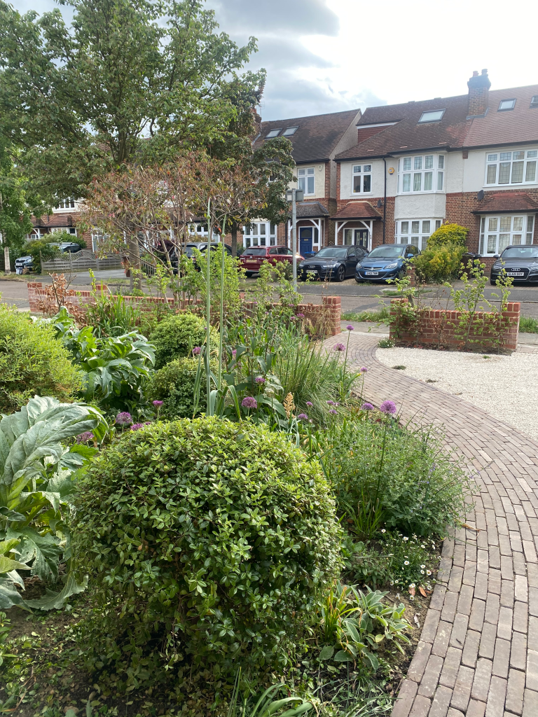 Permeable front garden with clay pavers path and gravel. Mixed planting